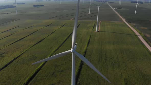 Aerial video lowering down on a wind generating spinning on a hot summer day in the midwest. alt