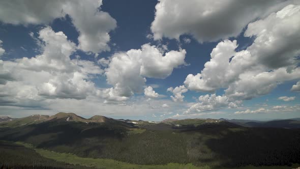 Time lapse of puffy clouds above mountain range and valley below alt