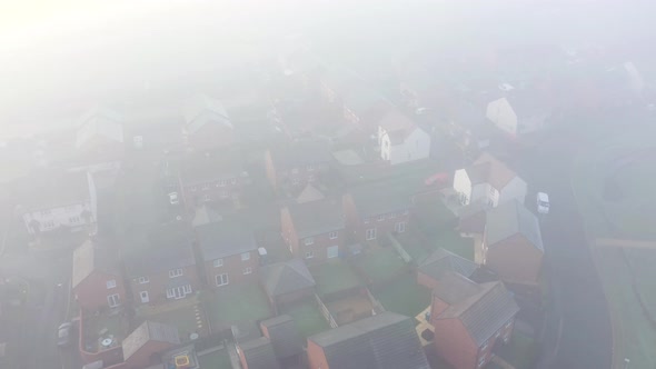 Aerial view of a residential estate covered by fog and clouds alt