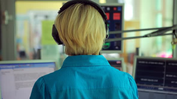 Female Radio Moderator in News Room Rear View