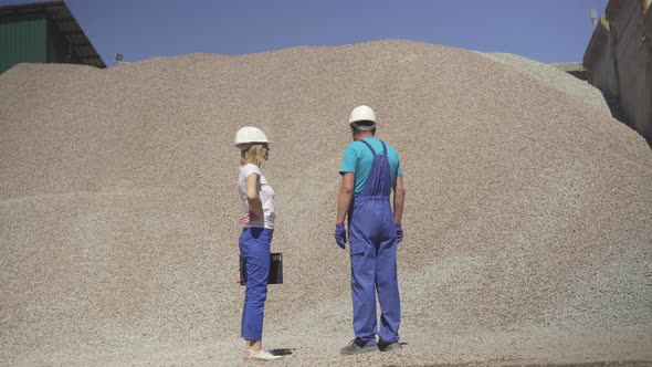 Wide Shot of Factory Workers Standing Outdoors in Front of Huge Pile of Crashed Stones. Caucasian alt