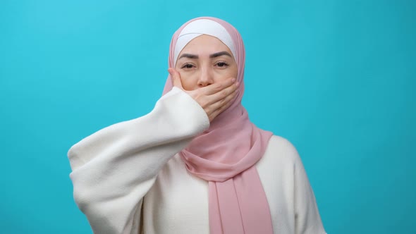 Sad and Serious Muslim Woman in Hijab Shaking Head Expressing No with Hand Over Mouth