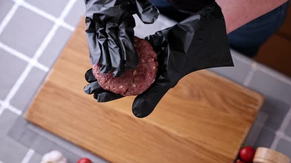 Woman Chef in Black Gloves Prepares Cutlets at Domestic Kitchen on a Wooden Cutting Board alt