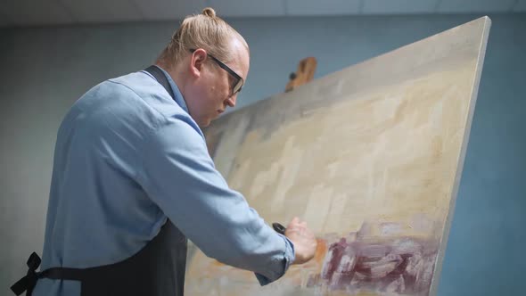 Creative Person at Work a Talented Adult Man Artist Covers the Canvas with Oil Paint Priming and alt