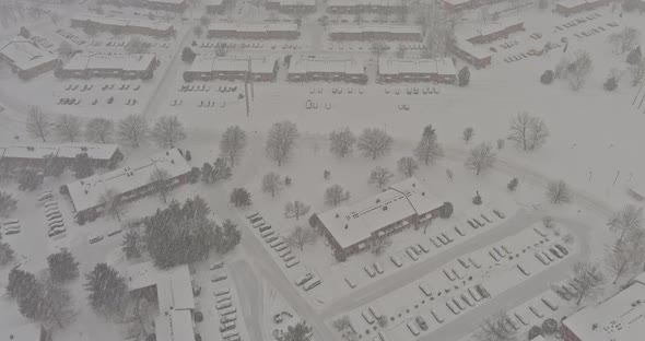 Snow Covered Trees in the Storm Clouds Above Snowfall Over Small Town Residential with Roofs Houses alt