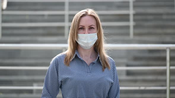 A Masked Girl in the Background of a Ladder in a Public Place of the City During a Quarantine alt