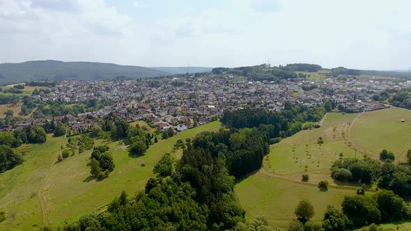 Flight with a DJI Phantom 4 Drone towards another rural, german village located on a hill in a beaut alt