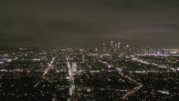 AERIAL: View Over Los Angeles at Night with Wilshire Boulevard Glowing Streets and City Car Traffic alt