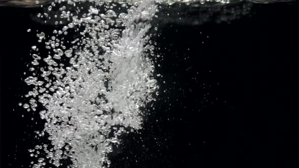 Slow Motion Stream of Water Drops Down in Aquarium on a Black Background alt