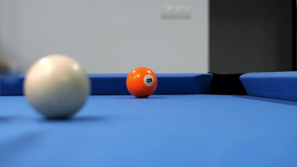 A man's hand strikes the white ball in an American billiard. Close-up of slow motion