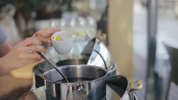 Close View of Female Hands with Manicure and Red Bracelet Filling Cup of Punch with a Ladle alt