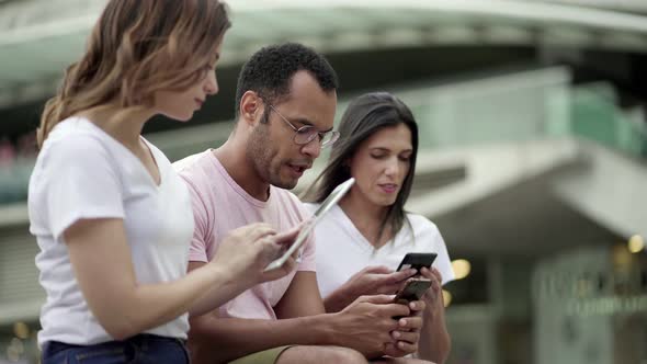 Group of Young People Using Devices on Street alt