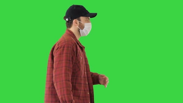 American Farmer in a Cap and Medical Mask Walks Along on a Green Screen, Chroma Key alt