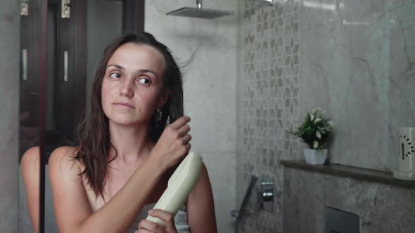 Young Woman Dries Her Hair with a Hair Dryer