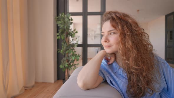Positive Lady with Red Curly Hair Resting in Living Room