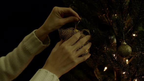 Woman Hanging Christmas Ball On Tree