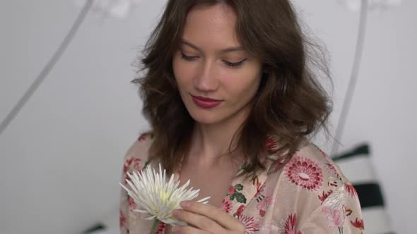 Girl winked with a flower in her hands alt