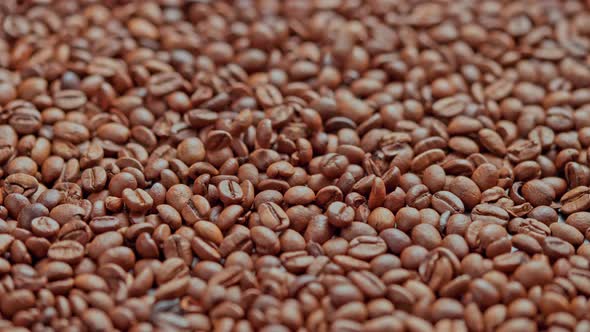Roasted Coffee Beans Drop in Slow Motion on Full Frame Background of Coffe Beans
