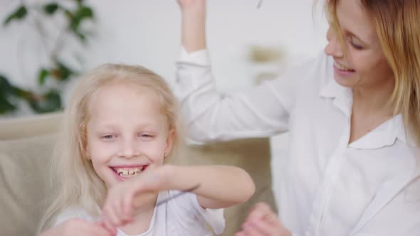Excited Little Girl and her Happy Mother Trying on Sunglasses at Home alt
