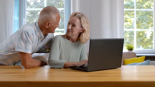 Elderly Couple Using Laptop Computer at Home Together alt