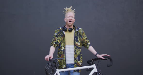Portrait of smiling albino african american man with dreadlocks looking at camera with bike alt