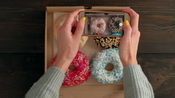 Woman's Hands Take Pictures with Smartphone of Delicious Donuts in Box alt