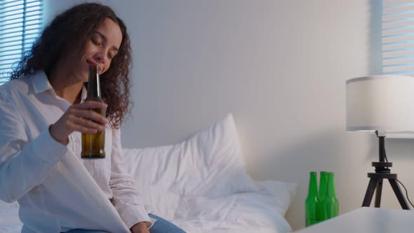 Drunk Latino woman hold beer bottle, feel hangover and dancing on bed. alt