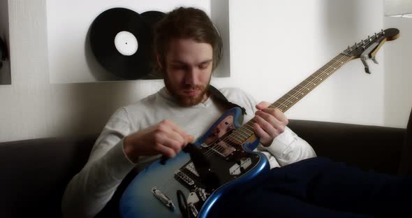 Young Man Plays the Electric Guitar at Home