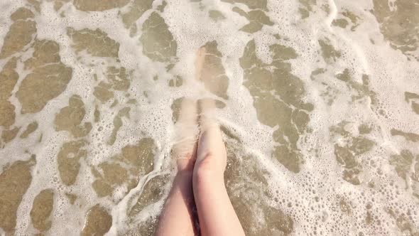 Female Legs in the Waves of the Sea Surf. alt