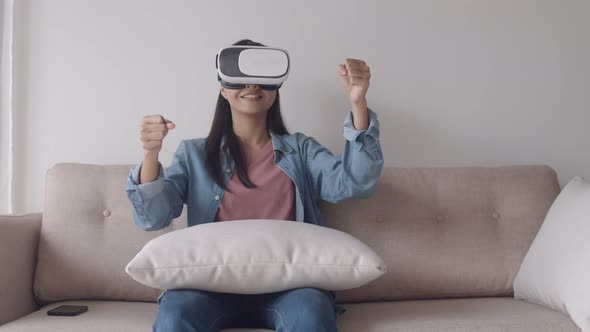 Attractive portrait young Asian woman wearing VR headset in the living room playing the game.