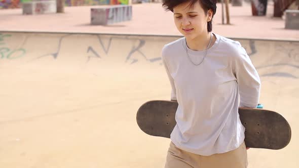Teenage Girl Holding Skateboard and Goes on Skatepark