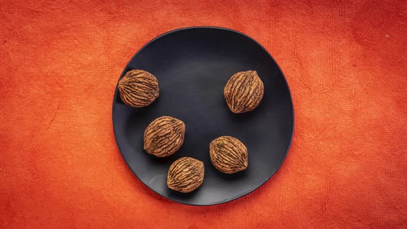 Black Walnuts in Shells Are Falling onto A Black Ceramic Plate - Stop Motion alt