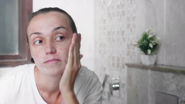 Young Woman is Applying Cream on the Face with Massage Movements at Bathroom