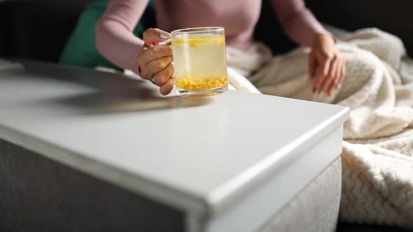 Slow Motion Woman's Hand Puts Pills Off the Table and Puts Sea Buckthorn Tea alt