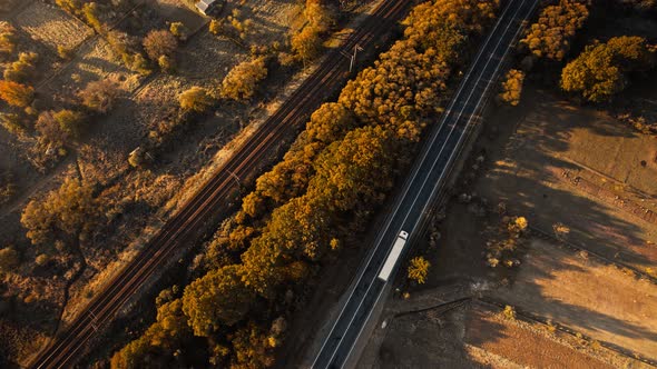 Top Down View Road with Cargo Vehicles and Railways at Sunny Sunrise in Mountain Valley in alt