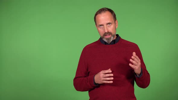 A Middleaged Handsome Caucasian Man Talks to the Camera  Green Screen Background