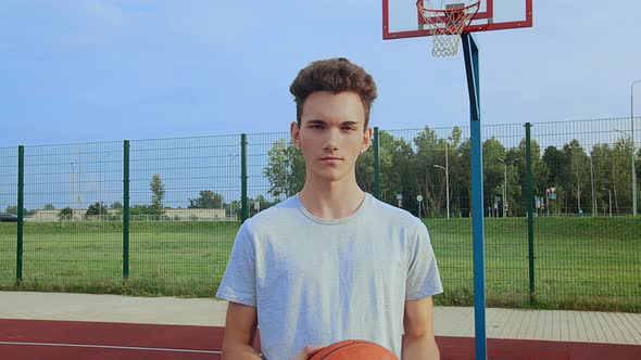 Guy on a Sports Court with a Basketball in His Hands Looking at the Camera alt
