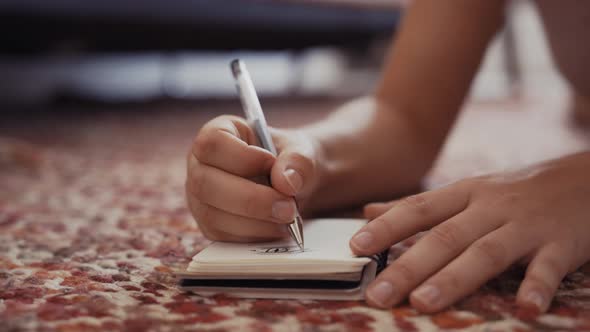Woman in lingerie lying on floor and writing in notebook alt