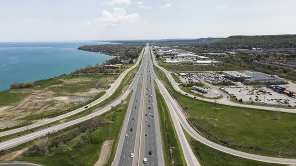 Aerial flyover traffic on highway beside Lake Ontario in Canada during sunny day. alt