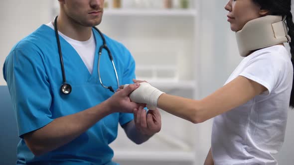 Doctor Fixing Wrist Elastic Wrap Female Patient in Foam Cervical Collar Rehab alt