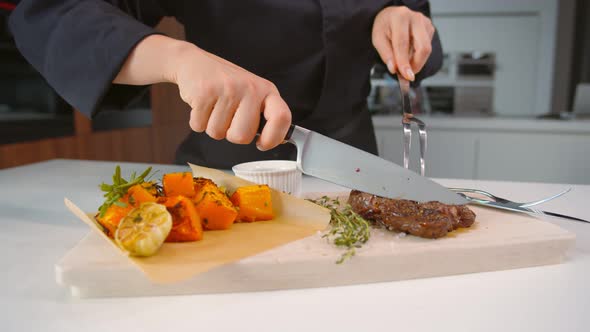 Close Up of Chef Cutting Beef Steak Served with Baked Spiced Pumpkin on alt