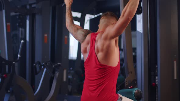 Male Training Back Muscles Doing Pulls Weight Exercise in a Gym