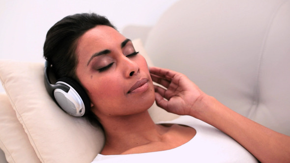 Attractive Woman Lying On Couch Listening To Music