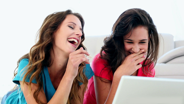 Attractive Amused Women Using Notebook Lying