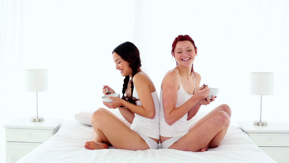 Happy Beautiful Women Trying Cereal Sitting On Bed