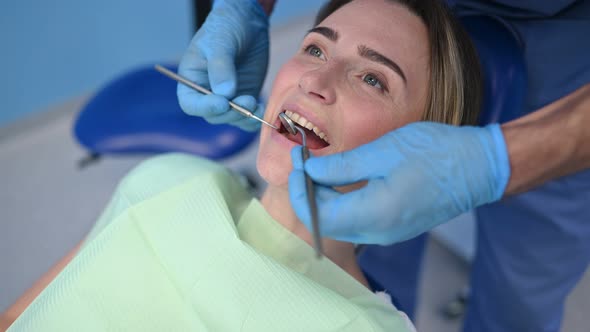 Dentist examining a patient's teeth using dental equipment in dentistry office. Stomatology concept