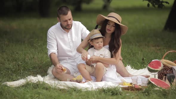 Parents and Their Son Eating Bakery at Picnic.