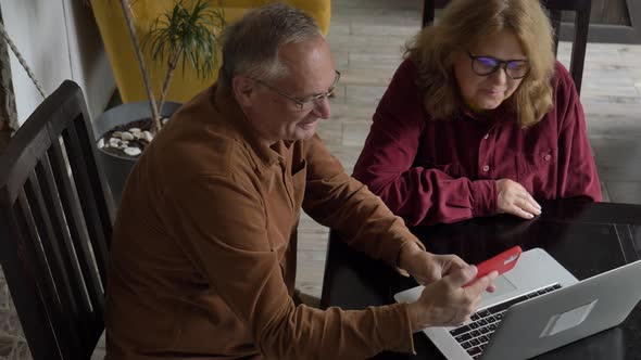 two elderly people surfing internet on laptop computer at home.