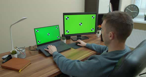 Male Video Editor Works on His Personal Computer with Big Green Screen Mock Up Displays.