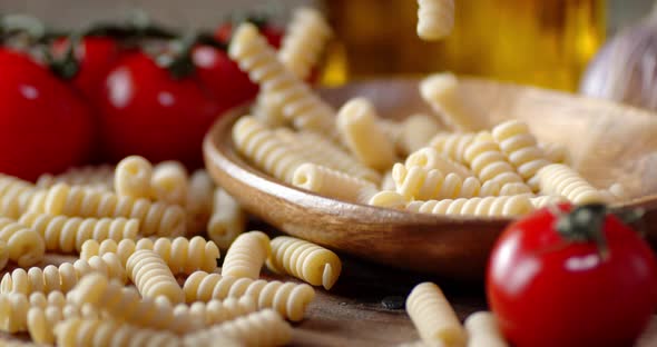 Dry Pasta Fusilli Falling on a Wooden Plate alt